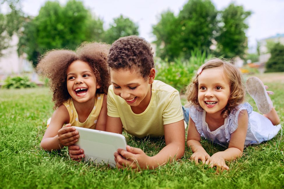 Happy children holding a tablet outside